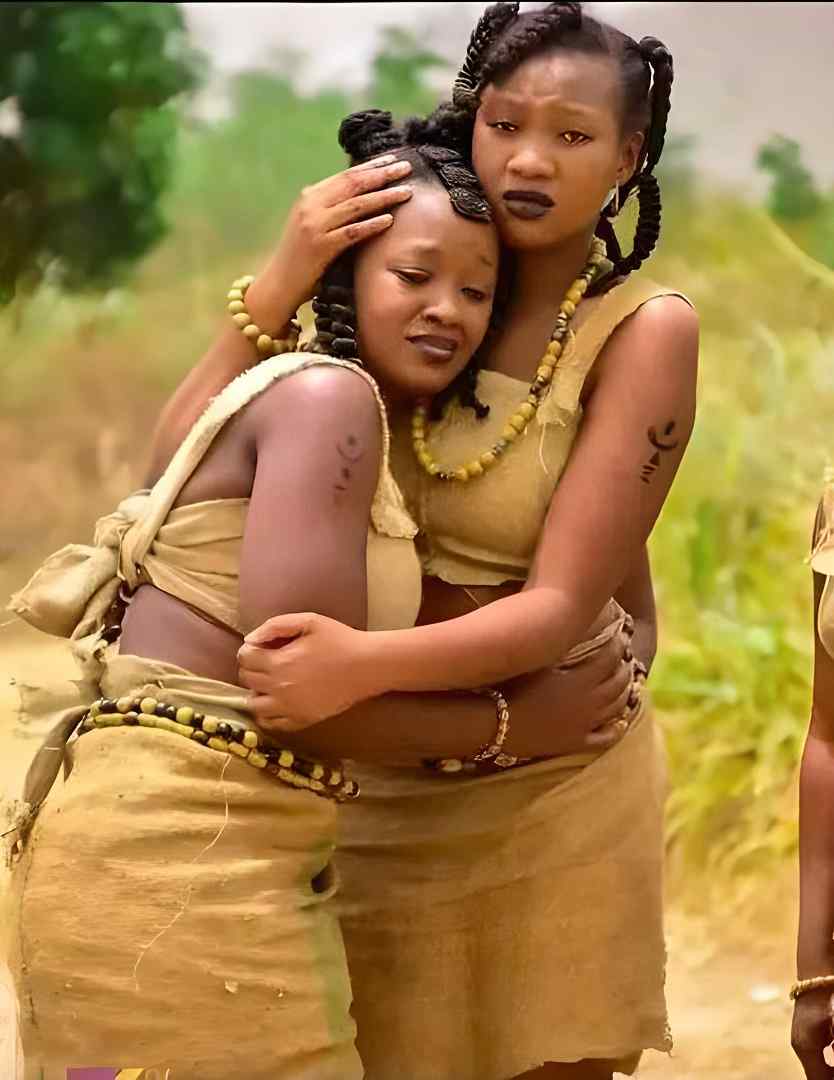 Two female actors in traditional african custome console one another in a movie scene