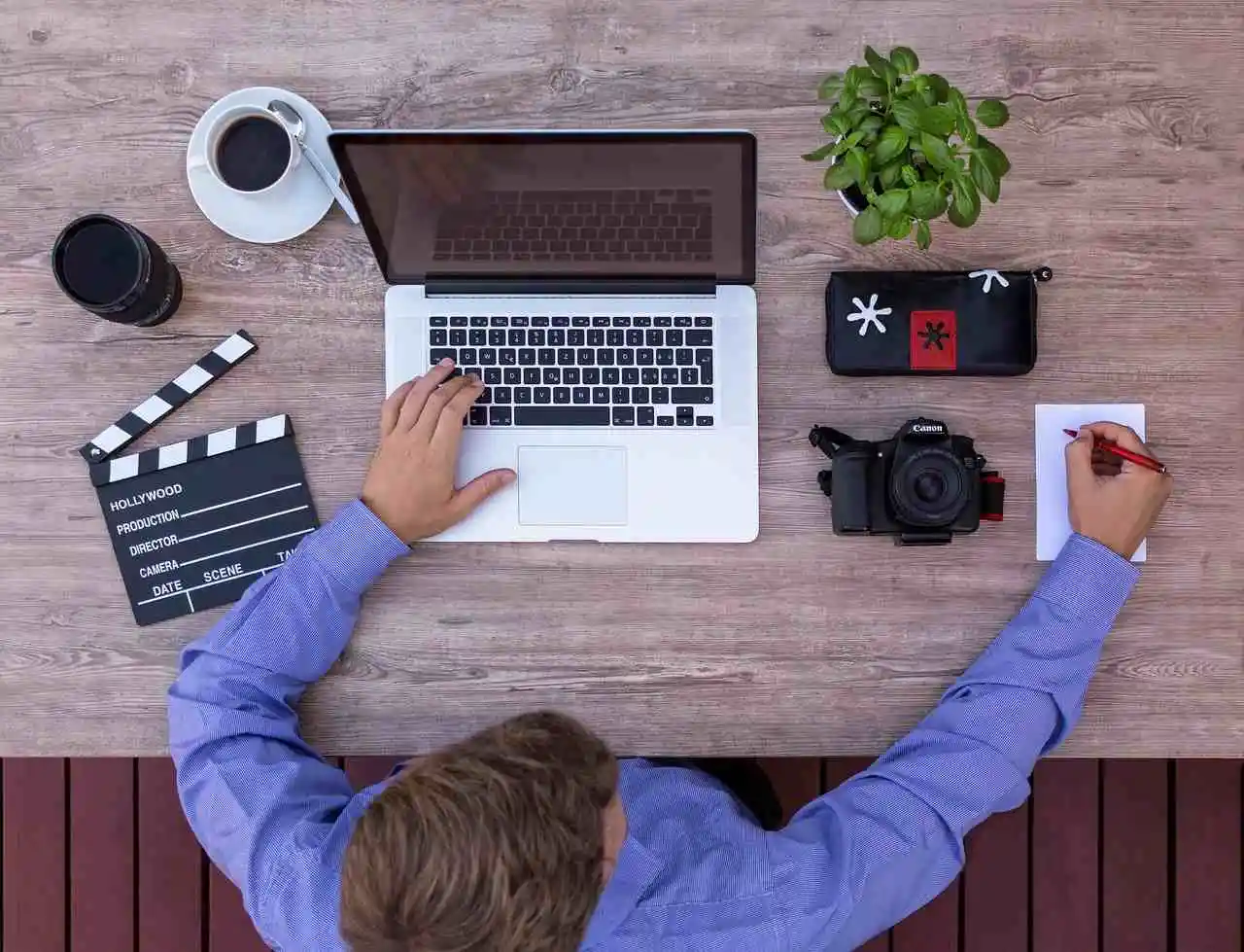 Screenwriter working on his laptop and taking hand written notes at the same time.